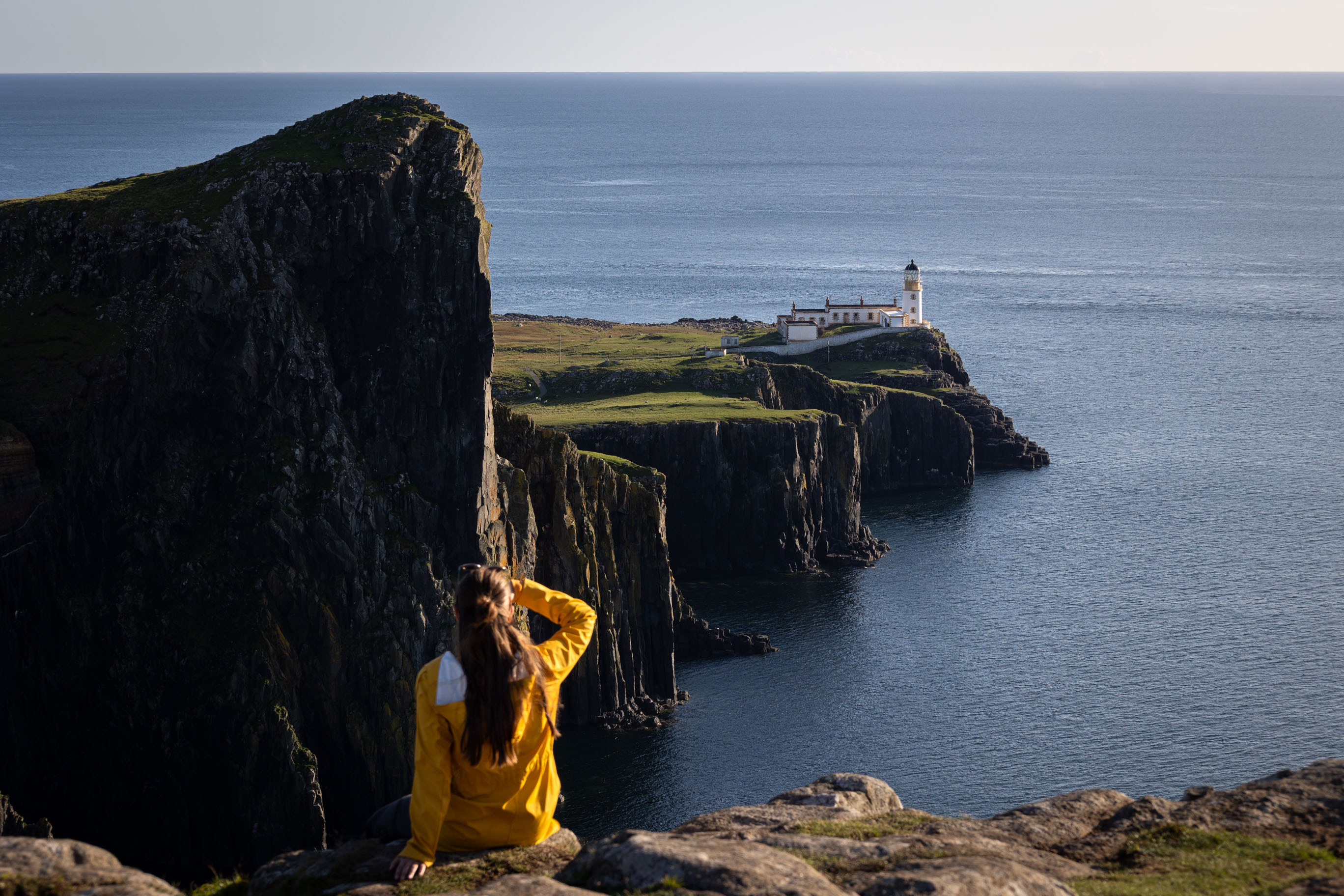 junge Frau blickt auf den Leuchtturm Neist Point in Schottland