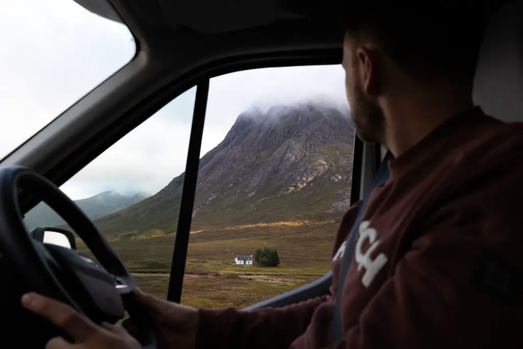 Fahrer blickt durch das Fenster aus seinem Wohnmobil auf einen Berg in Glencoe in Schottland